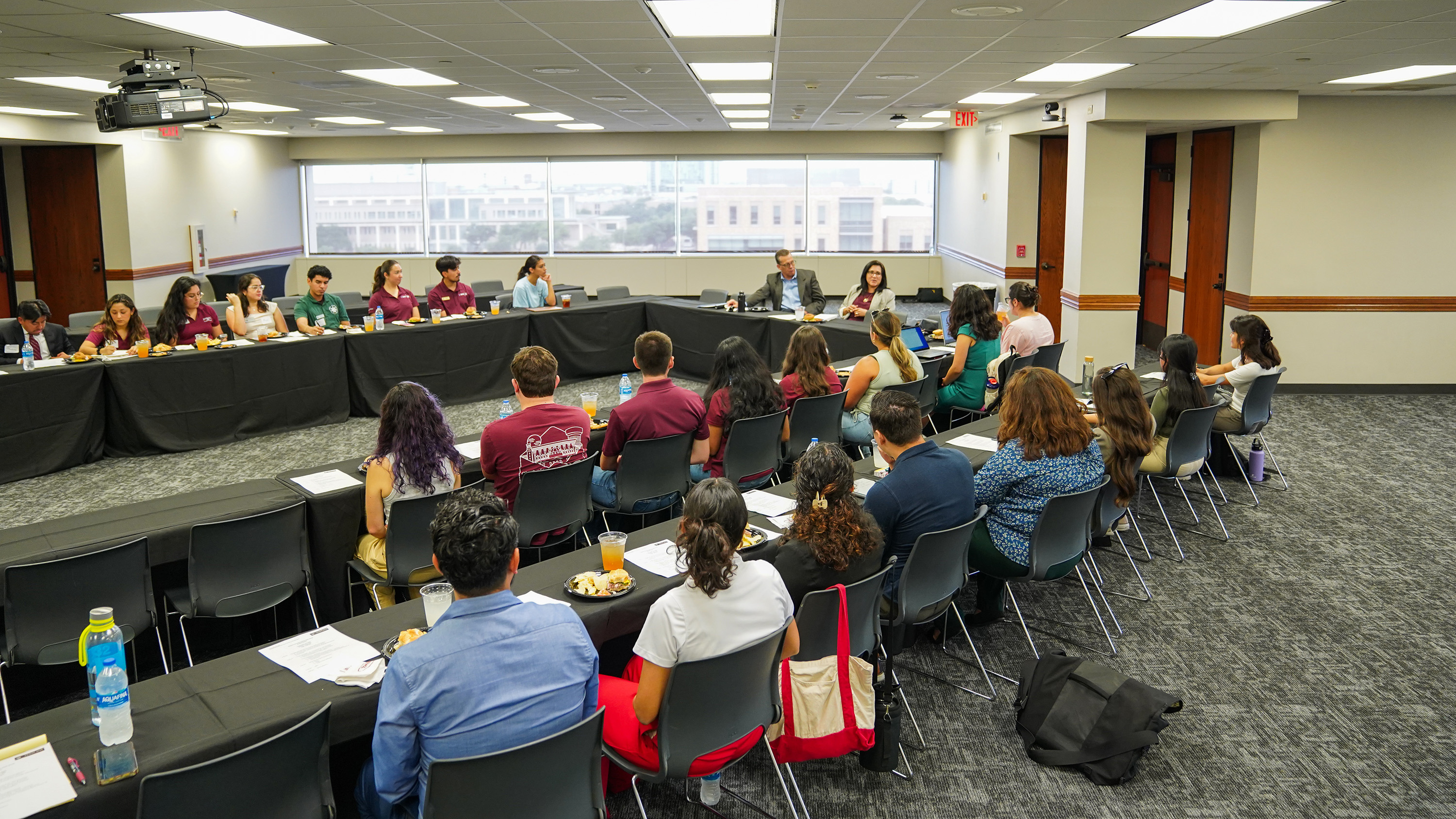 A conference room full of people eating lunch and watching a presentation.