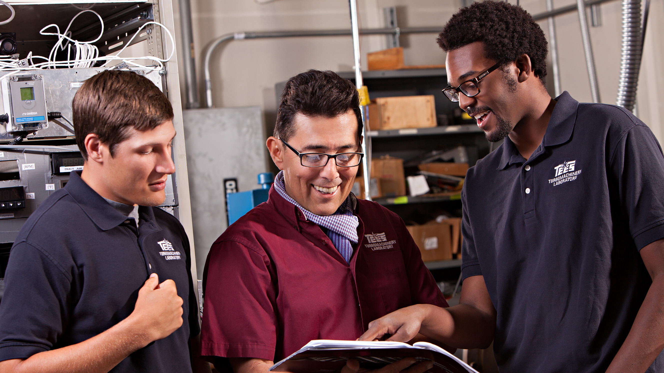 Three men looking at a folder of research data.